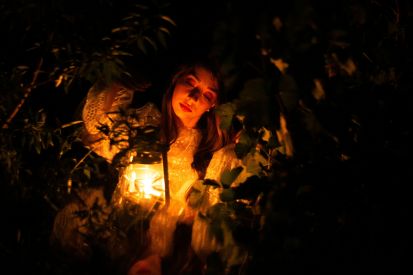A woman surrounded by darkness with light at the center as she considers myths about fibroids