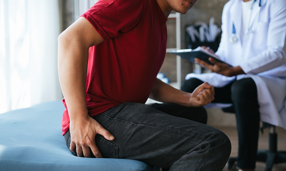 Man holding his backside at the doctors office