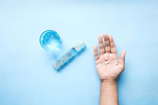 man holding medications tablets in his hand