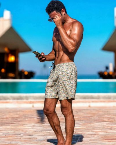 A shirtless man looking at his phone